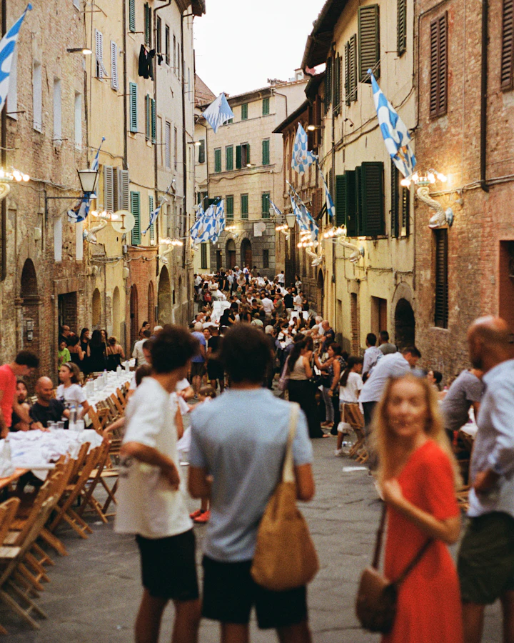 Lunghe tavolate in una via del centro storico piena di gente